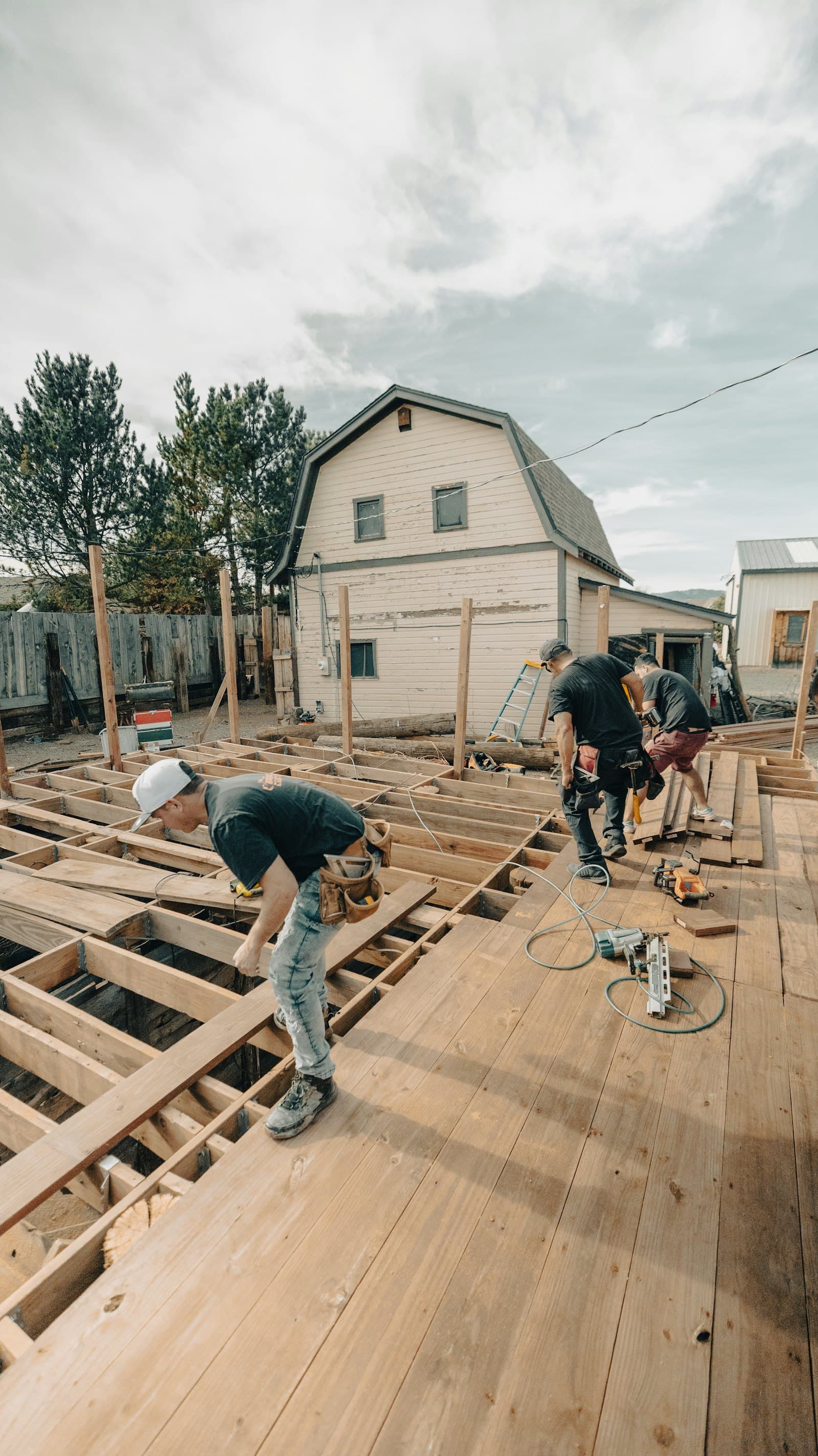 A crew building a wooden deck beside a house