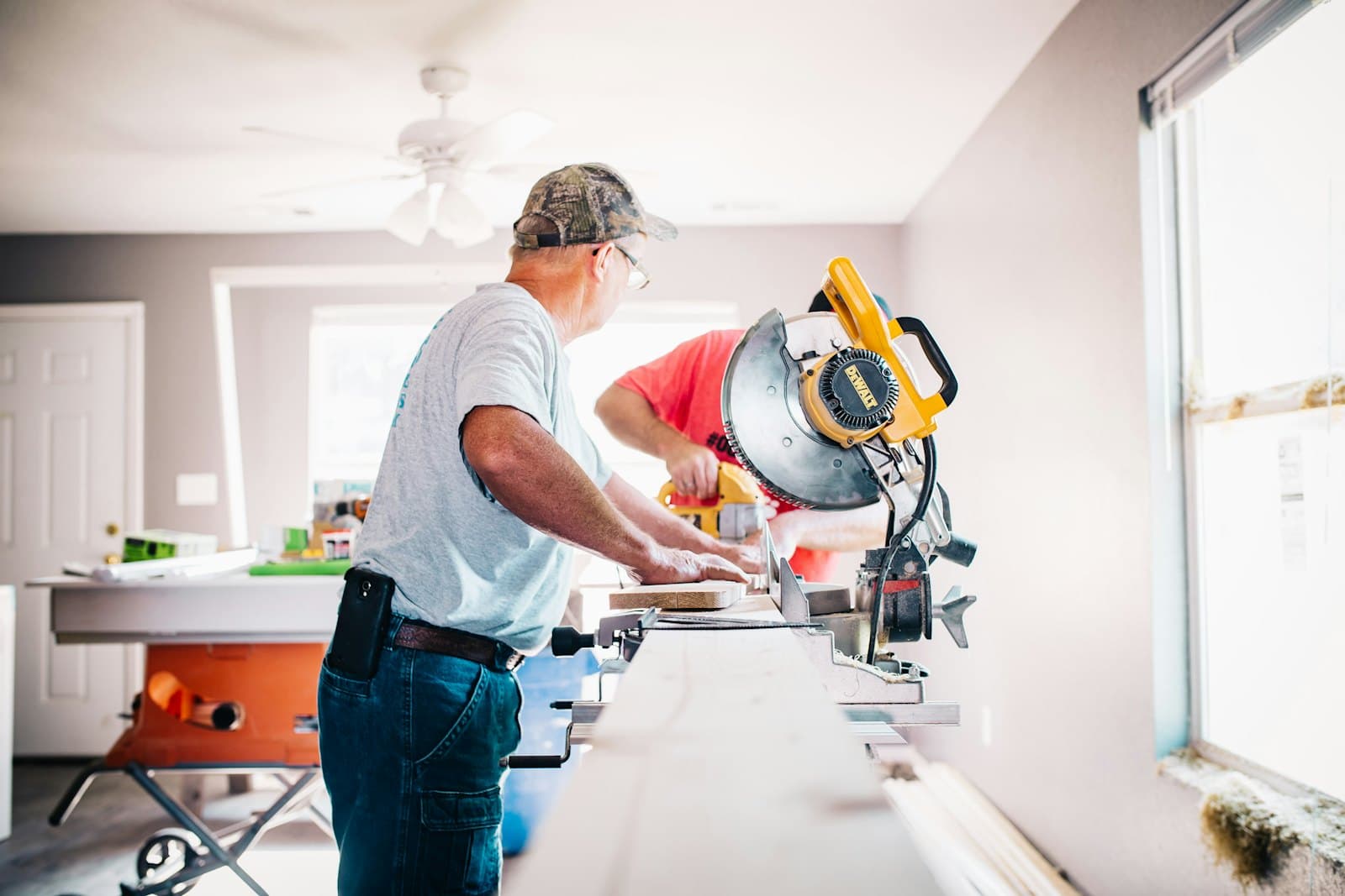 A handyman cutting trim on a mitre saw inside a house