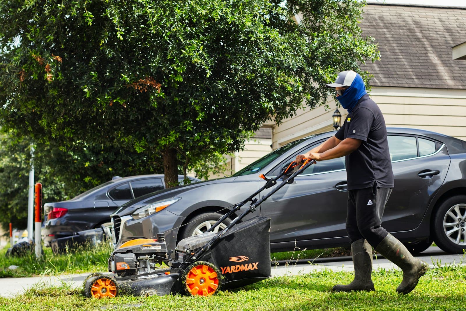 A crew member pushing a mower across a front lawn